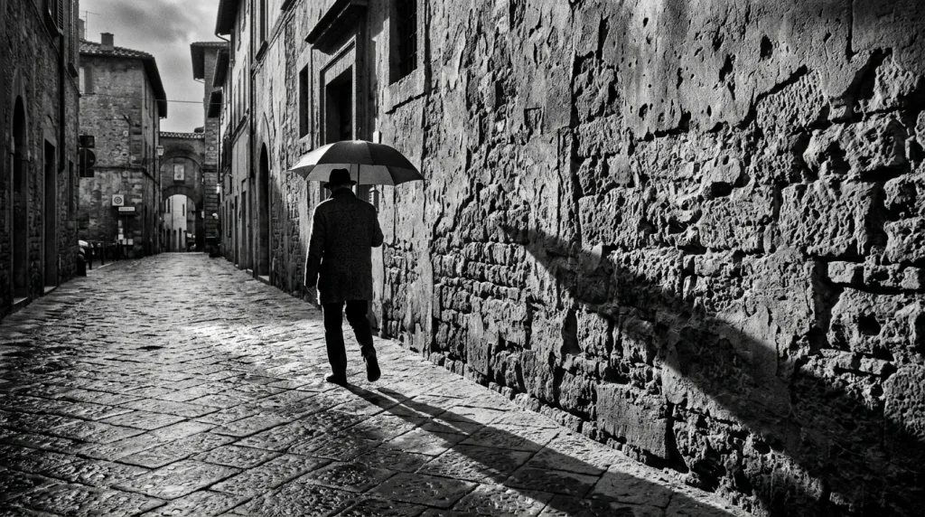 Candid black and white street photography capturing a pedestrian and dramatic shadows in a city.