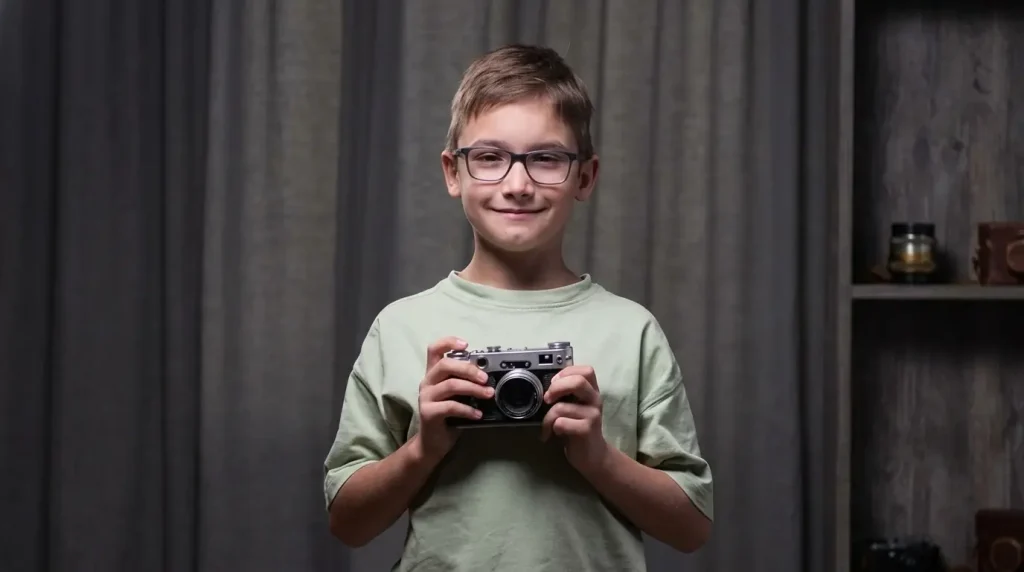 Boy holding an old-style film camera looking proud