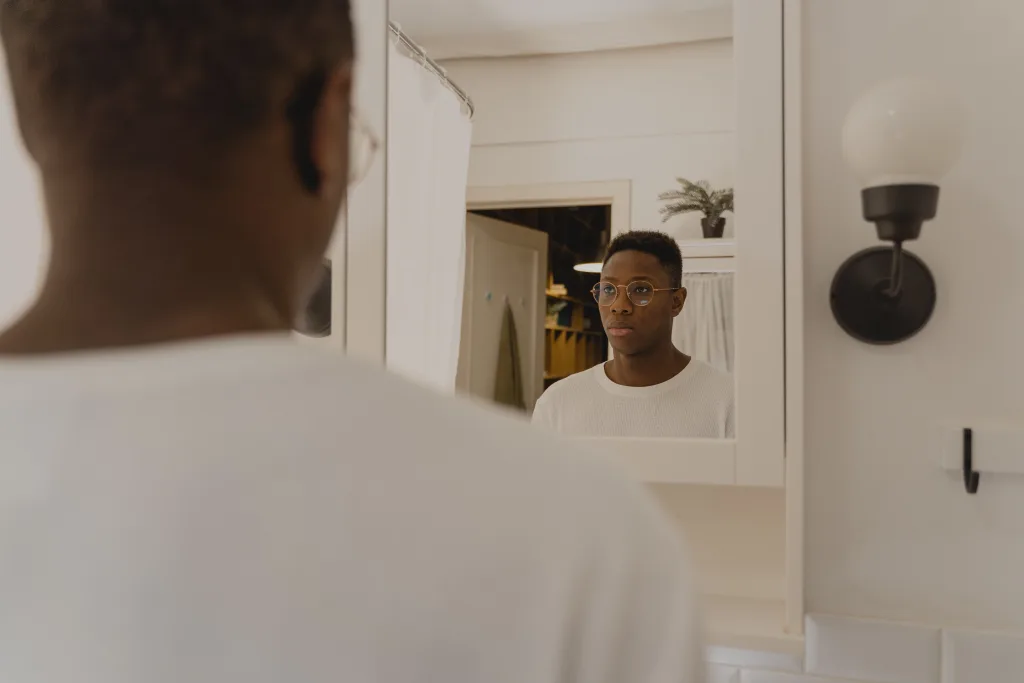 man reflecting in front of a mirror in soft natural light